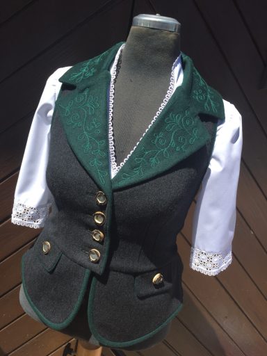 Dunkelgrüne Trachtenjacke mit weißen Ärmeln und goldenen Knöpfen.
