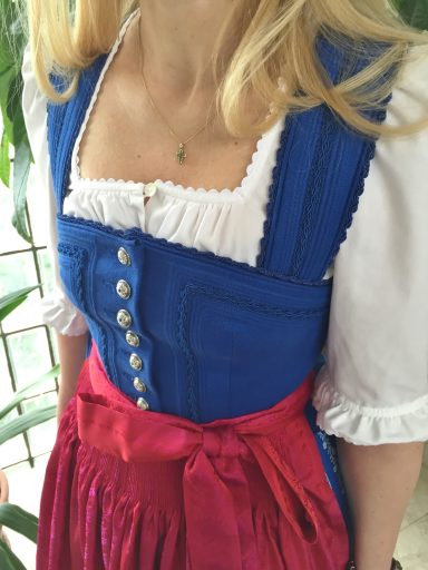 Traditionelles Dirndl in Blau und Rot mit Rüschen und Knöpfen.
