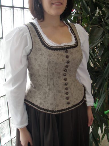 Frau trägt ein traditionelles, leicht besticktes Mieder mit weißen Ärmeln.