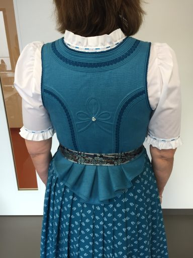 Rückansicht einer Tracht mit blauem Oberteil und Rock mit weißen Punkten.